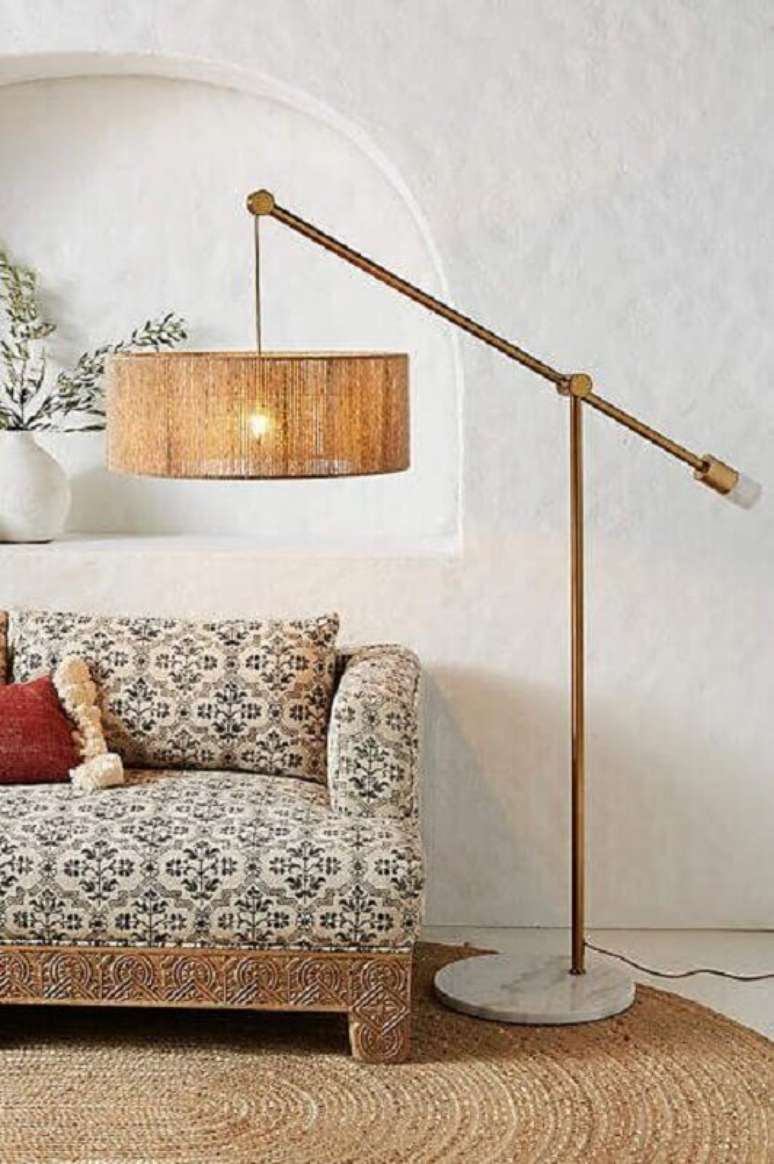 39. Decoração com abajur de pé rústico e sofá com estampa vintage – Foto: Anthropologie