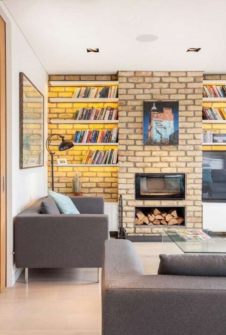 47. Sala com lareira decorada com prateleiras para livros e revestimento tijolinho – Foto: Houzz