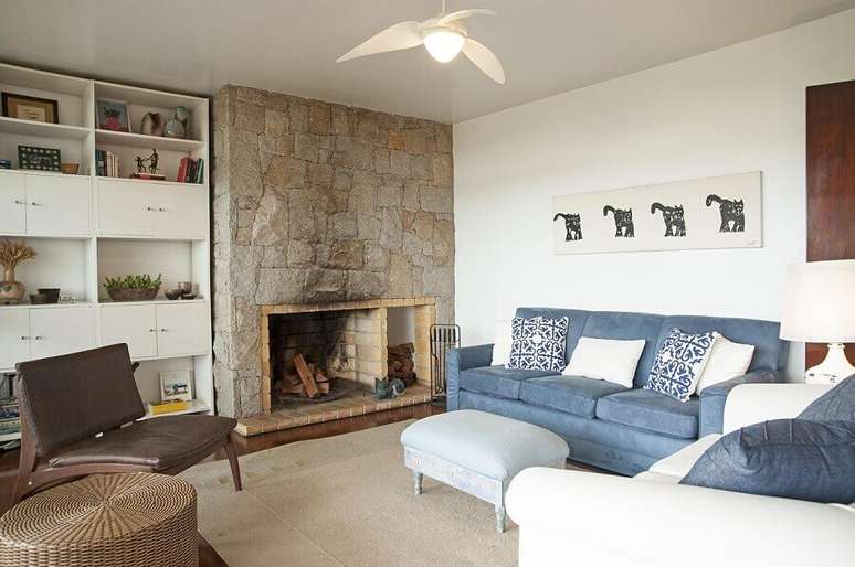 50. Sala com lareira rústica decorada com sofá azul – Foto: Renata Romeiro