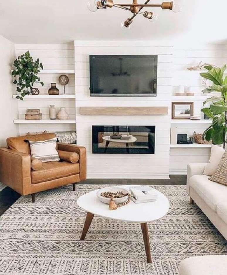 14. Cores claras para sala com lareira decorada com poltrona de couro marrom – Foto: Monarch Plank