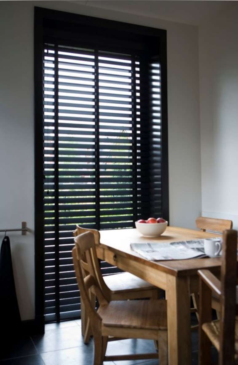 15. Sala de jantar com mesa de madeira e persiana preta – Foto Jasnos Hunters