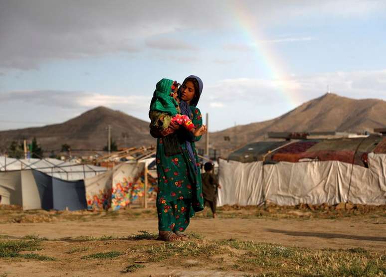 Menina afeg&atilde; deslocada pela guerra carrega crian&ccedil;a perto do abrigo em que vive em um campo de refugiados nos arredores de Cabul
20/06/2019 REUTERS/Omar Sobhani