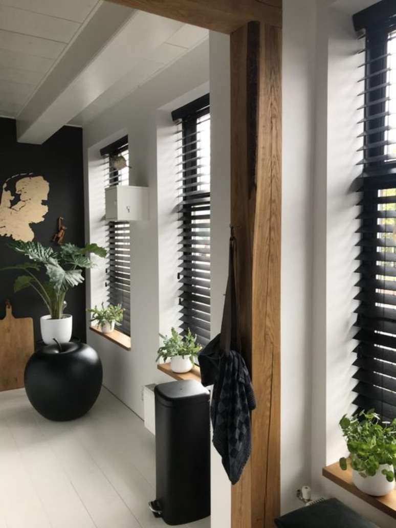 2. Casa com persiana preta horizontal e vasos de plantas decorando o corredor – Foto Studio Zinning