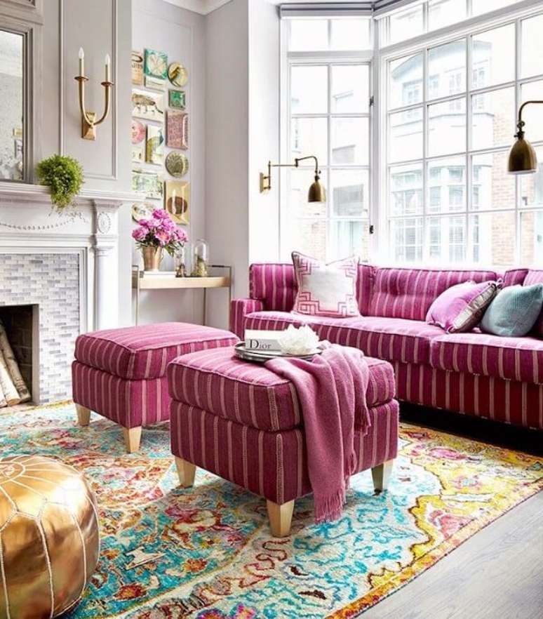 25. Sala de estar com sof&aacute; rosa e puffs listrados. Fonte: Homedit
