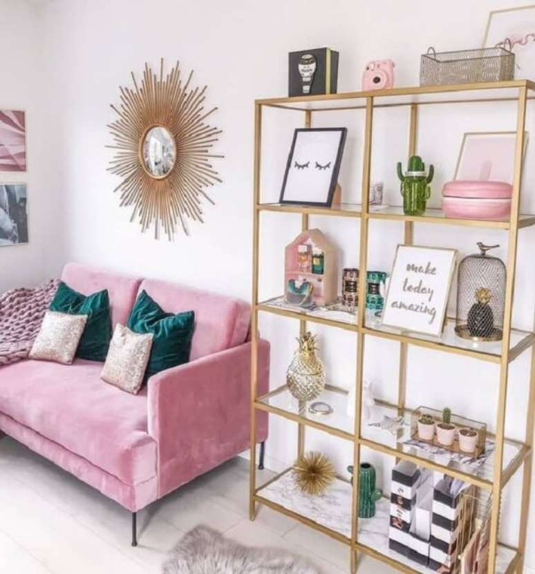 15. Sala de estar com prateleira em tom dourado e sof&aacute; rosa. Fonte: Pinterest