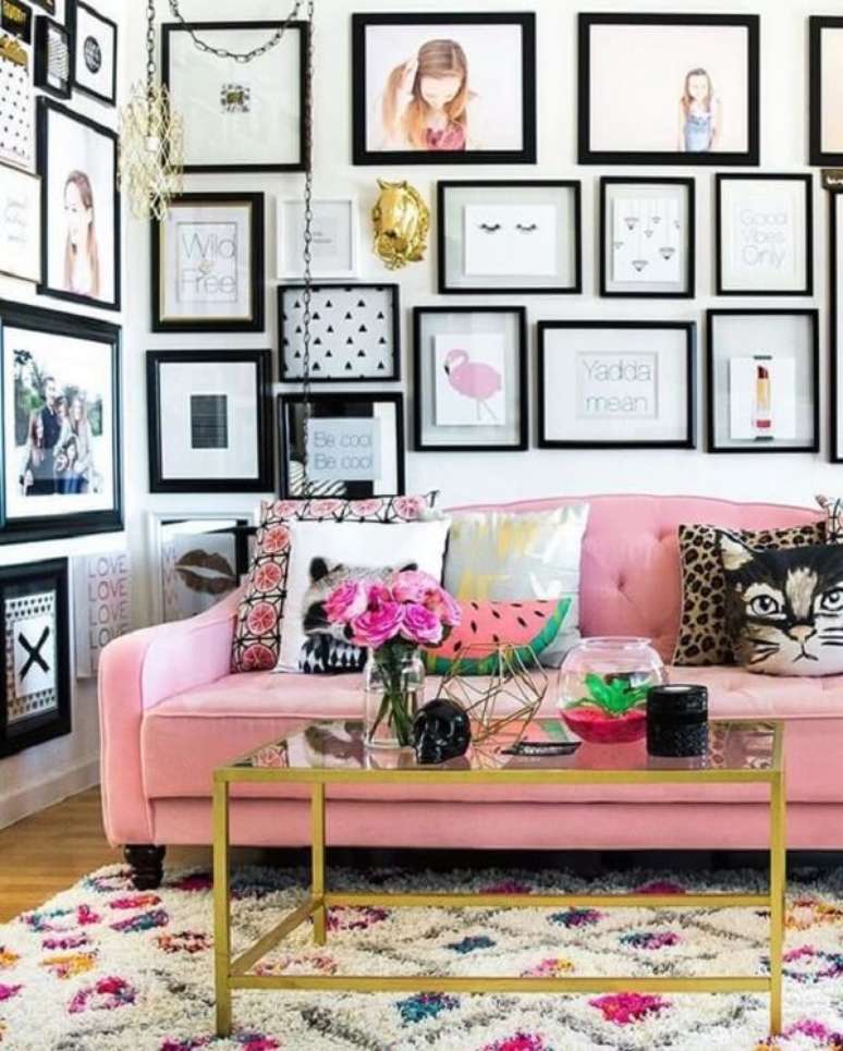 48. Sala de estar repleta de quadros decorativos e sof&aacute; rosa. Fonte: Fashionismo