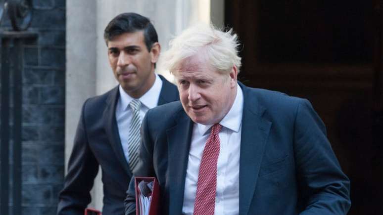 Ministro das finanças Rishi Sunak e primeiro-ministro Boris Johnson (à direita) estão se isolando depois que ambos entraram em contato com ministro da Saúde, cujo teste deu positivo para coronavírus