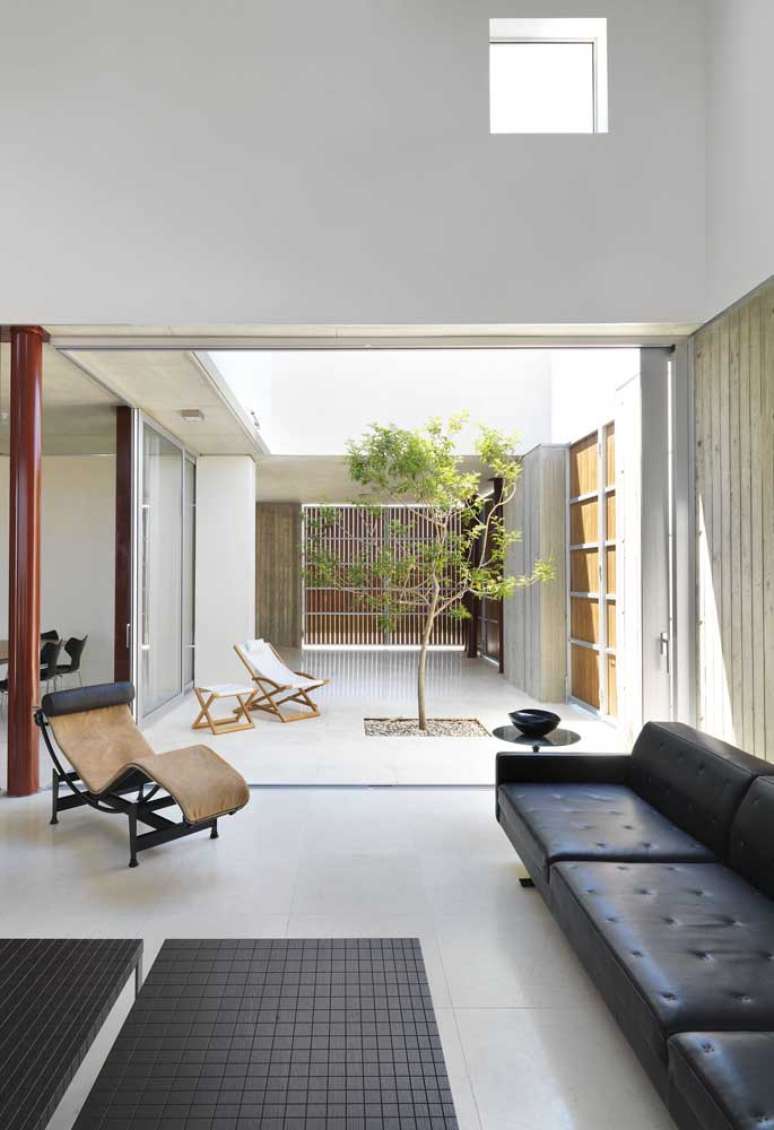 23. Sala com sof&aacute; estilo industrial de couro preto e jardim de inverno ao lado para iluminar o ambiente &ndash; Foto Pinterest