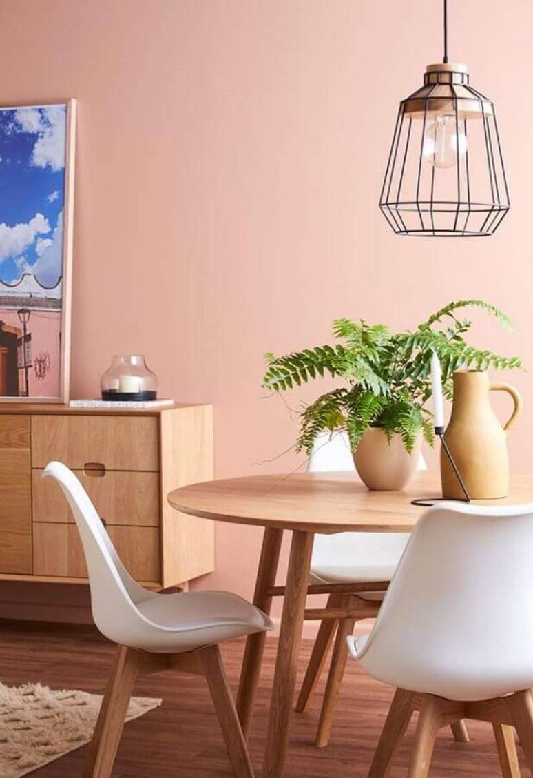 56. Sala de jantar decorada com mesa redonda de madeira e parede rosa chá – Foto: Pinterest