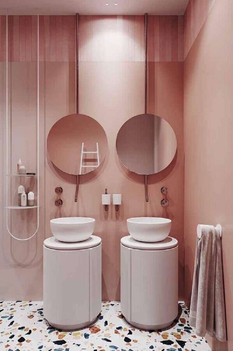 7. Banheiro moderno decorado com espelho redondo e parede rosa chá – Foto: Pinterest