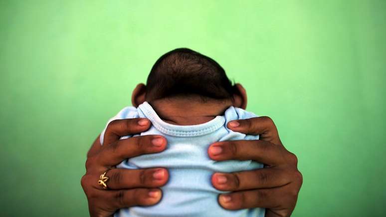 Bebê com microcefalia é erguido por sua mãe em Olinda, em foto de 2016