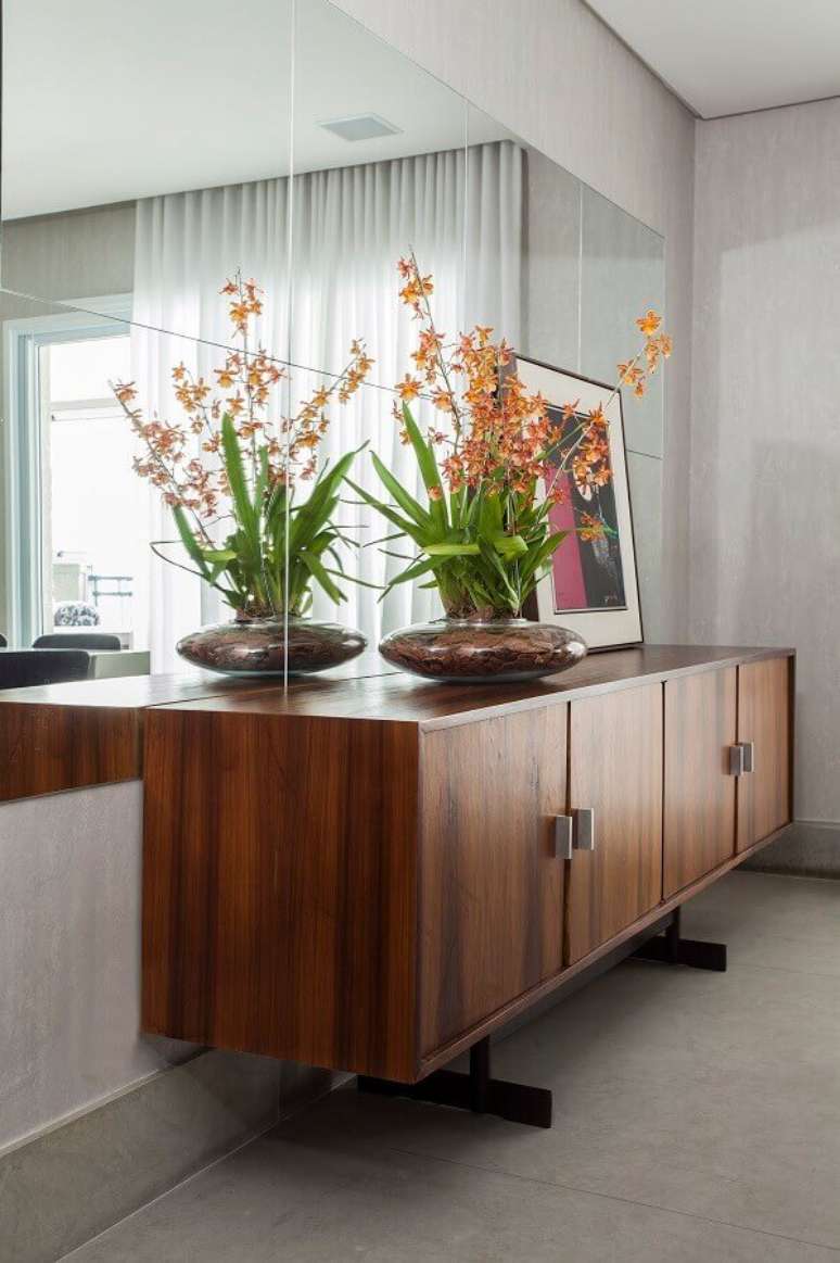 51. Sala de jantar decorada com parede espelhada e buffet de madeira &ndash; Foto: A Gazeta