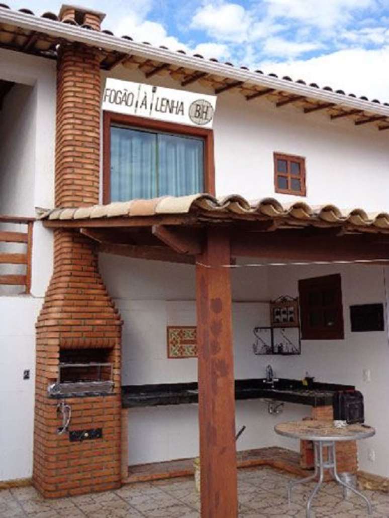 18. Chaminé para churrasqueira na área externa com bancada de granito preto e mesa redonda – foto Pinterest