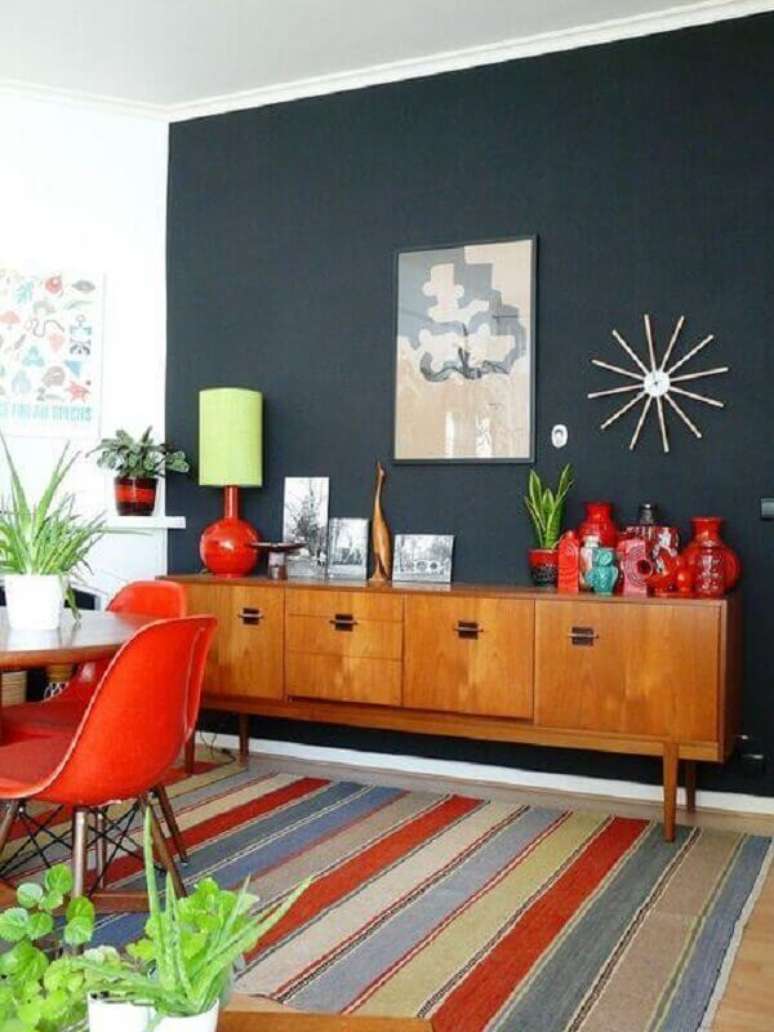 22. Buffet de madeira para sala de jantar decorada com parede preta e tapete listrado colorido &ndash; Foto: Pinterest