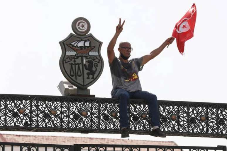Manifestante comemora destituição de premiê no topo do Parlamento, em Túnis