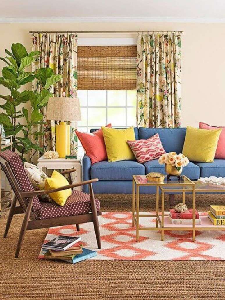 27. Objetos de decoração para sala de estar com almofadas coloridas e poltrona de madeira – Foto: Better Homes and Gardens