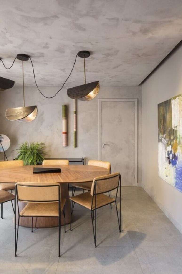 6. Luminária para sala de jantar moderna decorada com parede de cimento queimado e mesa redonda de madeira – Foto: ArchDaily
