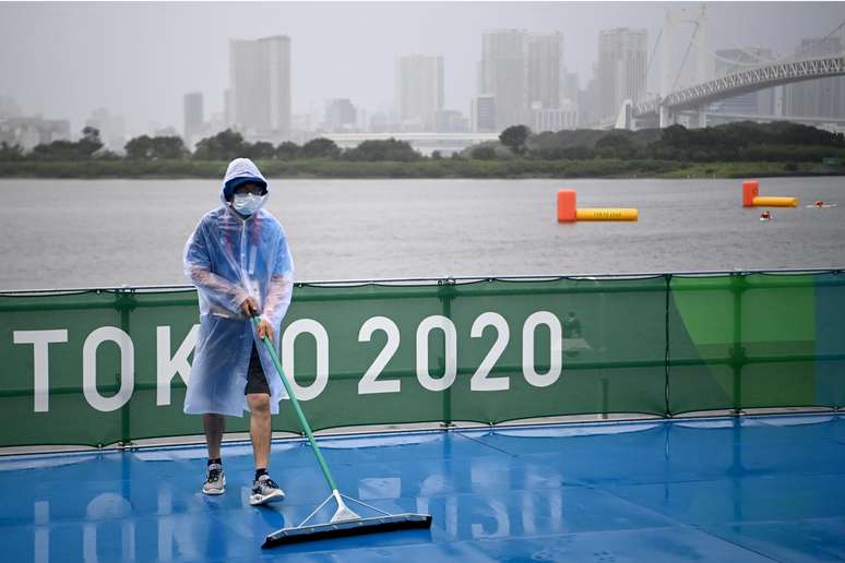 Voluntário tenta escoar a água de área reservada para os competidores da prova de triatlo em Tóquio