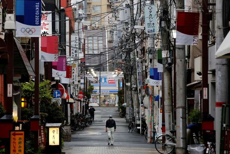 Homem usando máscara caminha em rua decorada com bandeiras da Olimpíada Tóquio 2020 em Tóquio
07/05/2021 REUTERS/Kim Kyung-Hoon