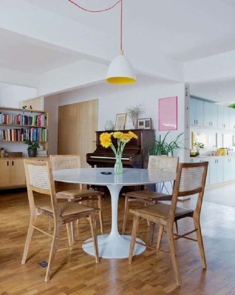 67. Luminária simples para sala de jantar decorada com mesa redonda e cadeira de madeira com encosto de palha – Foto: Histórias de Casa