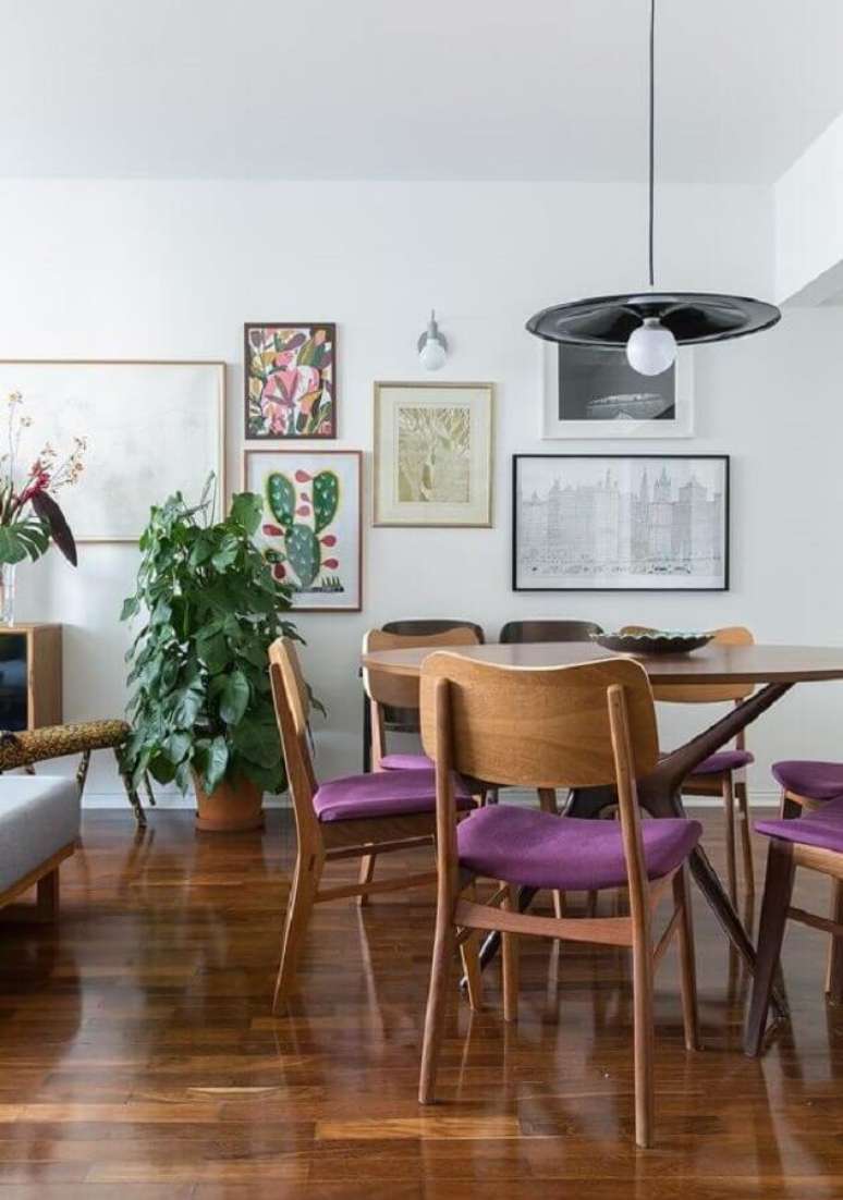 69. Luminária simples para sala de jantar decorada com quadros de parede e cadeira estofada roxa – Foto: Histórias de Casa