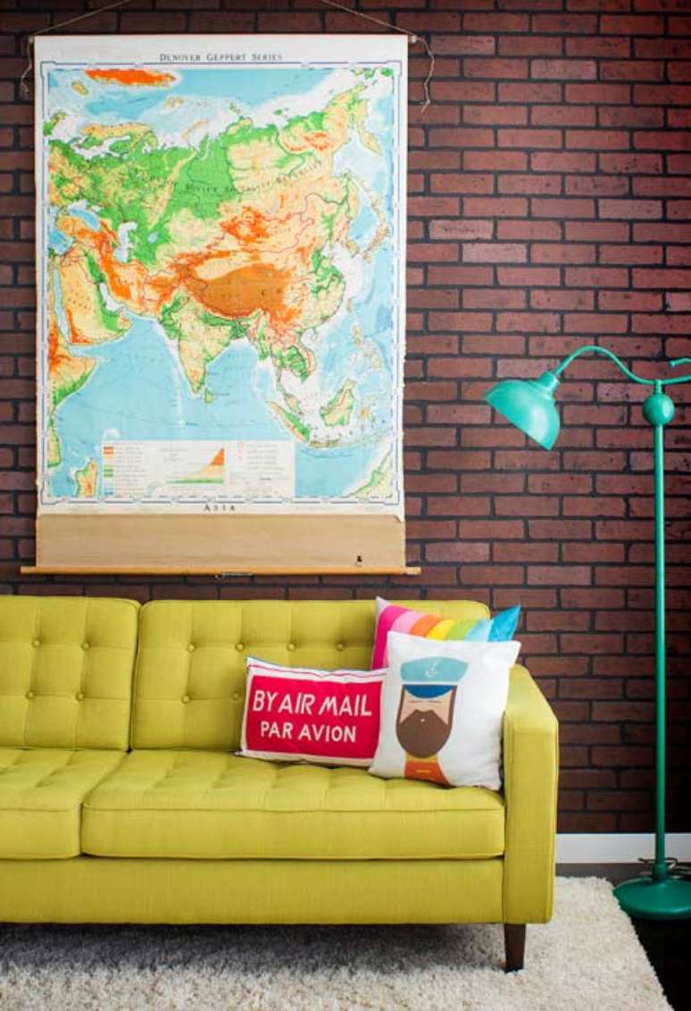 45. Parede de sala decorada com papel de parede de tijolinho e quadro de mapas coloridas com almofadas divertidas no sofá amarelo — Foto Pinterest