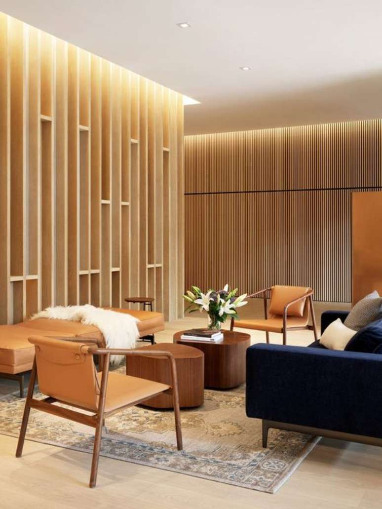 59. Sala de espera com sof&aacute; azul marinho cadeiras de madeira e chaise de couro &ndash; Foto Dezeen