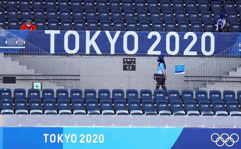 Espectadora caminha embaixo de placa da Tóquio 2020 no estádio onde é disputado o torneio olímpico do hóquei
24/07/2021 REUTERS/Siphiwe Sibeko