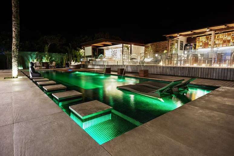 6. A iluminação noturna traz ainda mais beleza para a casa com piscina verde. Projeto de Unlimited Pool