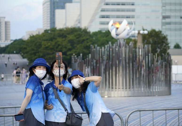 Voluntárias das Olimpíadas fazem selfie com a pira olímpica em Tóquio