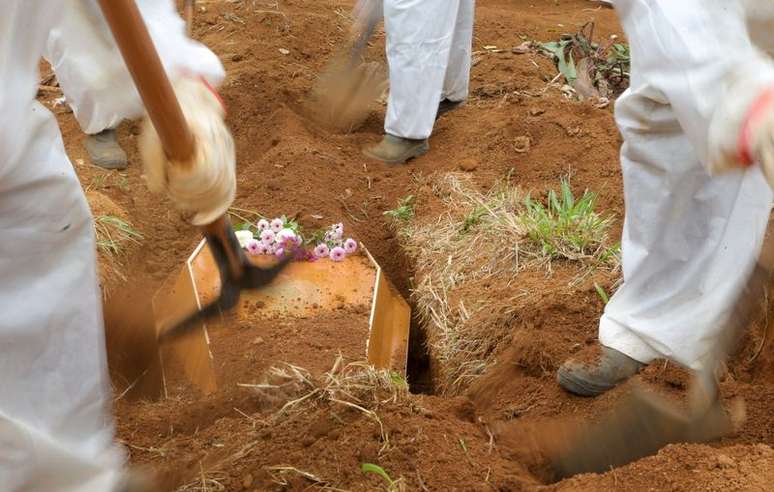 Gravediggers wear protective suits as they work during the burial of Benedito Rodrigues da Silva, 83, who died from the coronavirus disease (COVID-19), at Vila Formosa cemetery in Sao Paulo, Brazil March 17, 2021. REUTERS/Carla Carniel