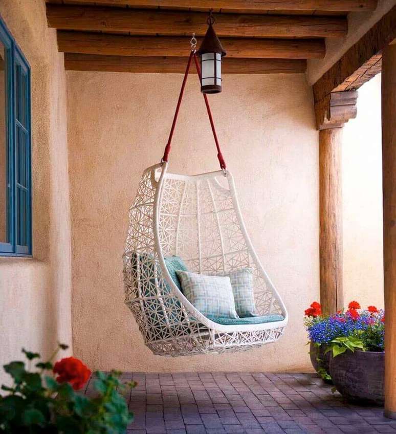 32. Cadeira de balanço suspensa para varanda rústica decorada com vasos de chão – Foto: One Kindesign