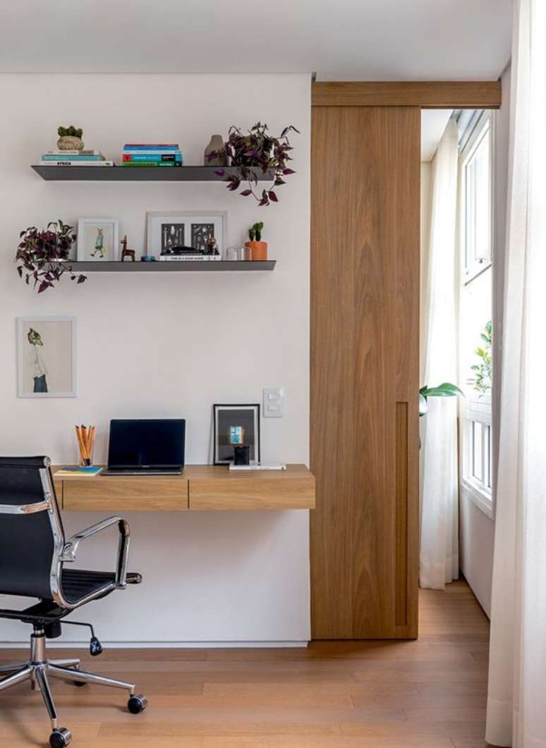 37. Home office na sala de estar moderna feita de madeira e com cadeira confortavel – Foto Revista casa e Jardim