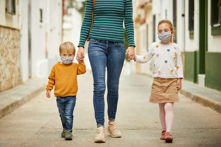 Imagem de mulher andando de mãos dadas com duas crianças