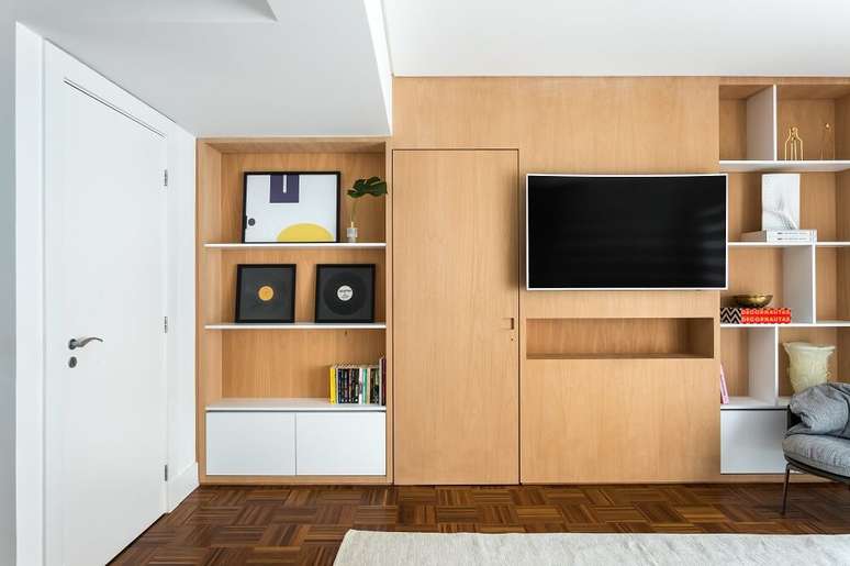 10. O painel com nichos da TV foi desenhado incorporando a porta do closet ao conjunto. Foto: Eduardo Macarios