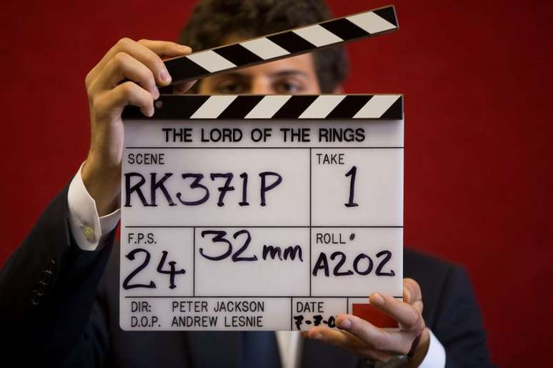 Assistente de galeria posa com claquete durante filmagem de "O Senhor dos Anéis" em casa de leilões de Londres
31/07/2014
REUTERS/Neil Hall