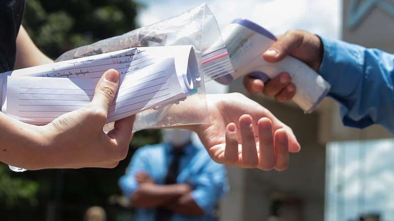 Jovem tendo temperatura medida antes de prestar Enem 2020