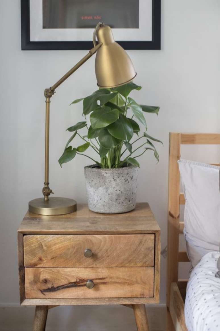 17. Mesa de cabeceira retrô de madeira com luminária e vaso de planta – Foto Apartment Therapy