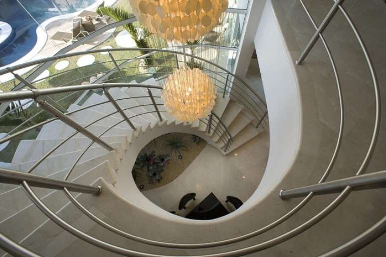 3. Invista em um lustre para escada pé direito alto e deixe o projeto ainda mais elegante. Projeto por Aquiles Nicolas Kílaris