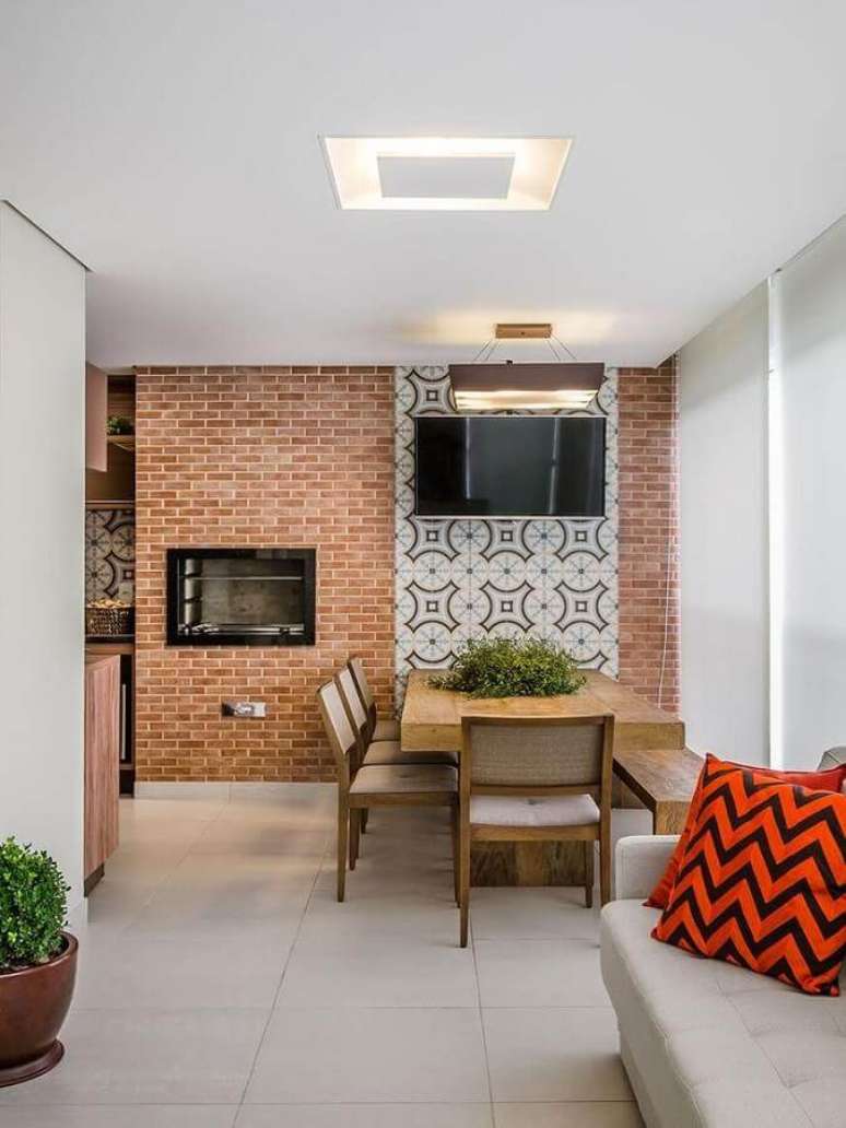 46. Mesa de madeira e parede de tijolinho à vista para decoração de apartamento com varanda gourmet – Foto: Mariana Lobo
