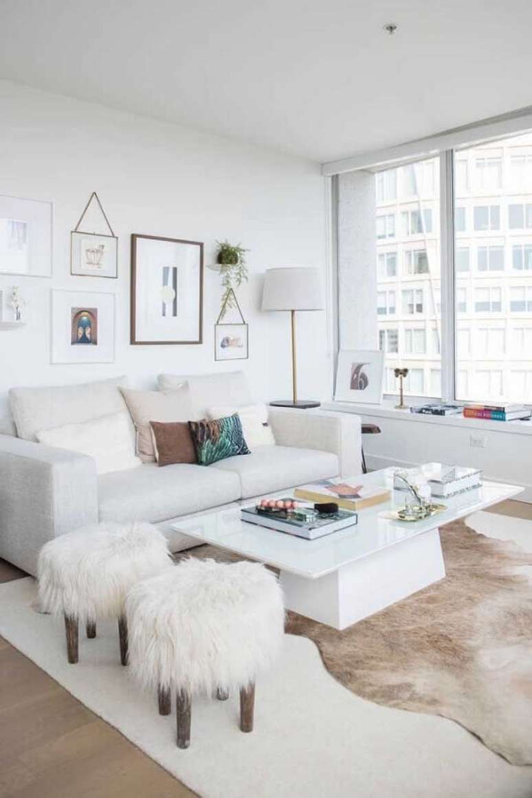 53. Sala de estar branca decorada com tapete de couro e puff banqueta redondo – Foto: Apartment Therapy