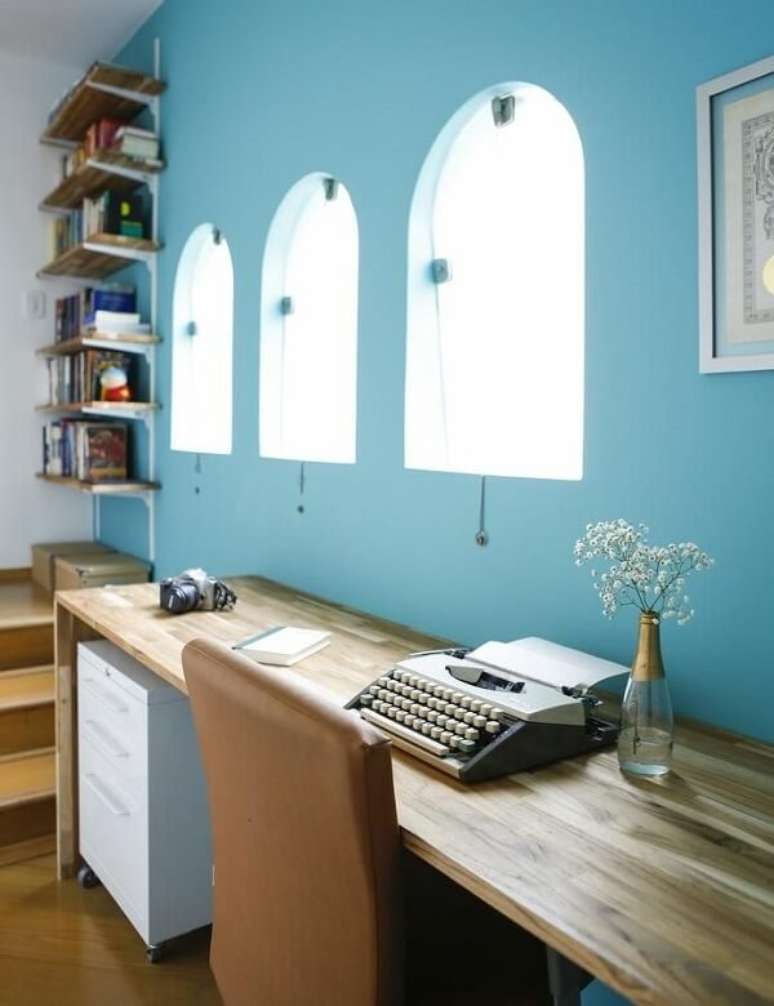 25. Home office com parede azul, escrivaninha de madeira e gaveteiro branco. Projeto de Buji Decoração Reuso