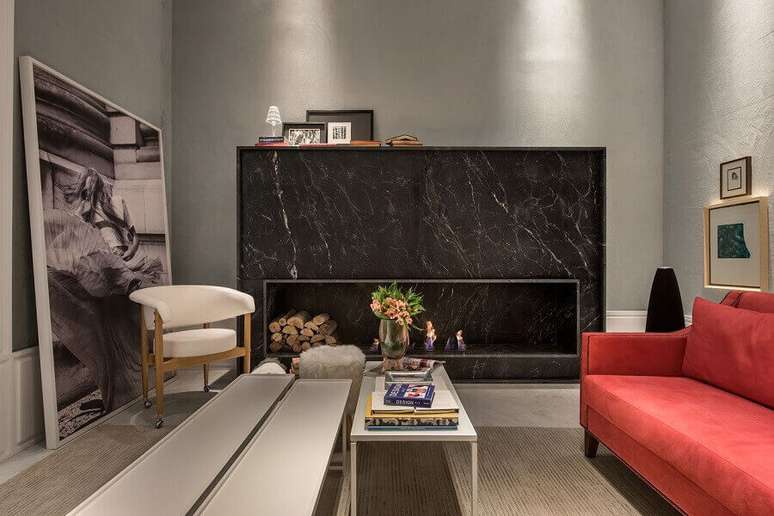3. Sala de estar com lareira revestida com mármore preto e sofá vermelho luxuoso – Foto Lidia Maciel