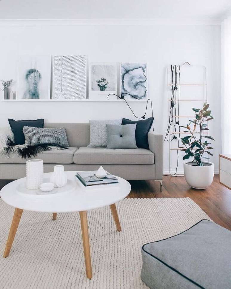 2. Decoração estilo escandinavo para sala cinza e branco com mesa de centro redonda e prateleiras para quadros – Foto: Pinterest