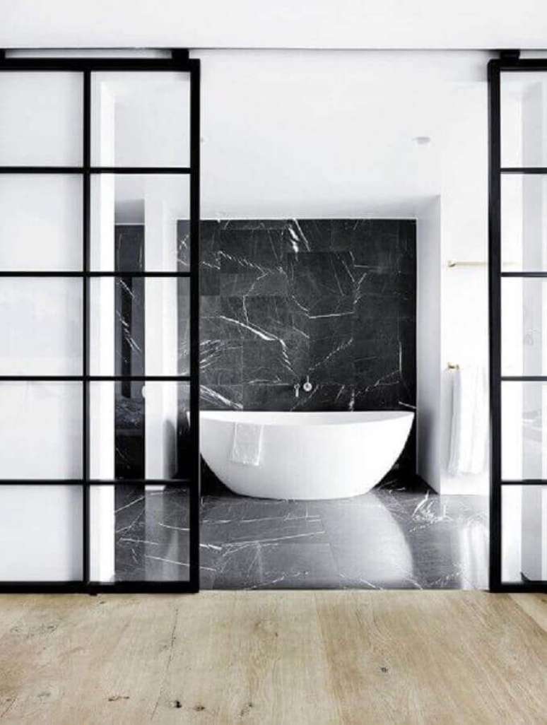 22. Banheiro moderno com revestimento de mármore preto e banheira branca – Foto Space Cph