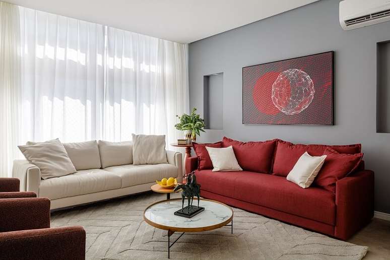 6. O sof&aacute; vermelho quebra a neutralidade e conversa diretamente com as poltronas e quadro. Foto: Dhani Borges