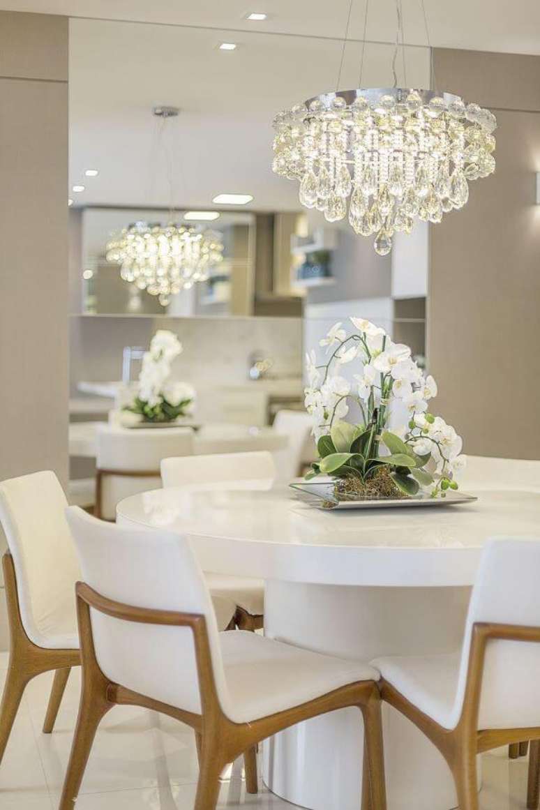 36. Mesa de jantar branca redonda com lustre de cristal e cadeiras brancas -Foto Homify
