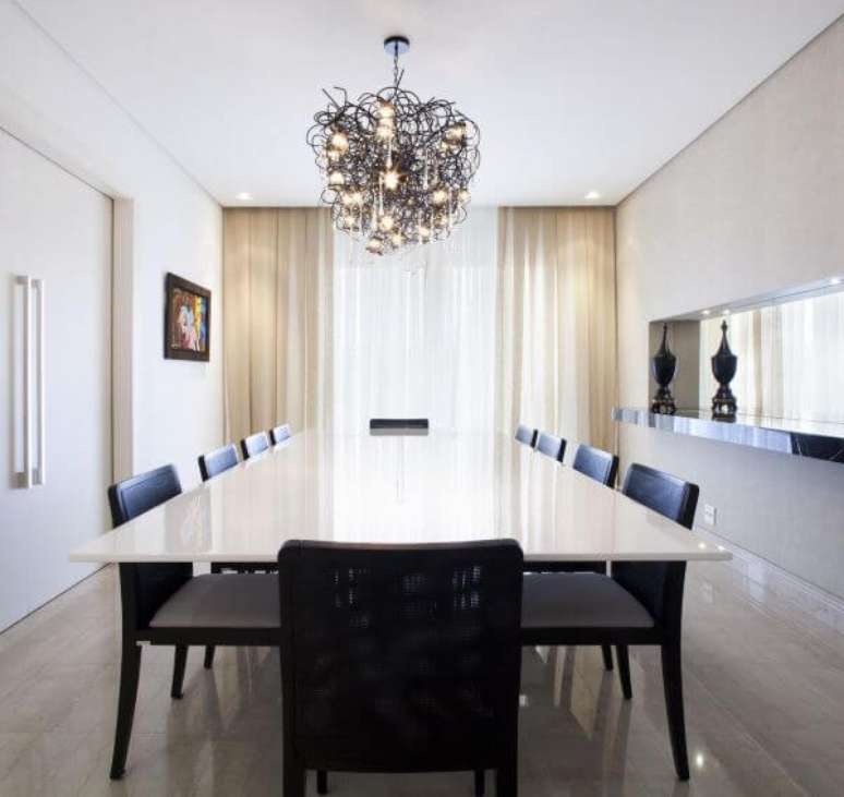 26. Mesa de jantar branca com cadeiras pretas e lustre moderno no centro -Foto charquitetura