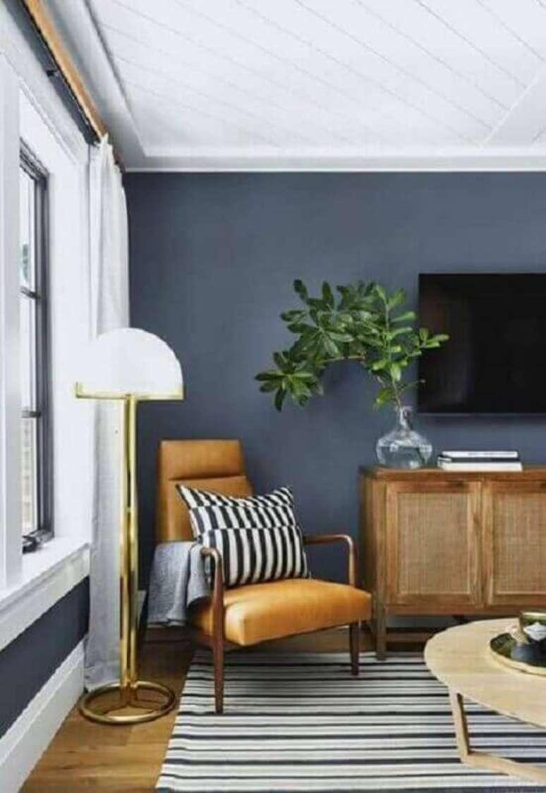 29. Poltrona de madeira com estofado cor caramelo para decoração de sala de TV cinza – Foto: Pinterest