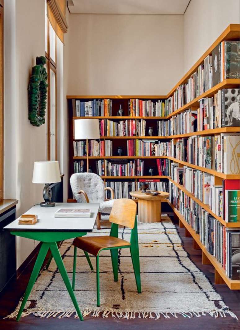 26. Estante de canto de madeira para livros variados com escrivaninha verde – Foto Architextural Digest